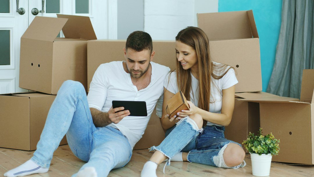 Couple sitting on the floor of a new home planning the move on a tablet